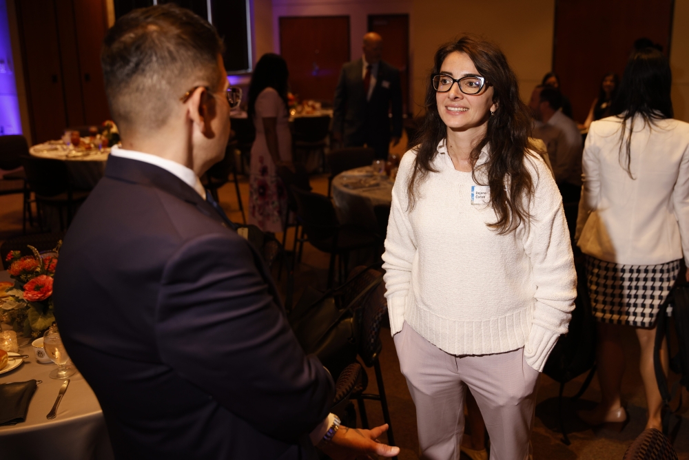 A woman wearing glasses speaks with another attendee during the reception.